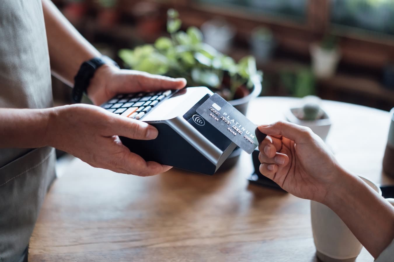 Customer tapping a credit card on a contactless countertop payment terminal at a retail store