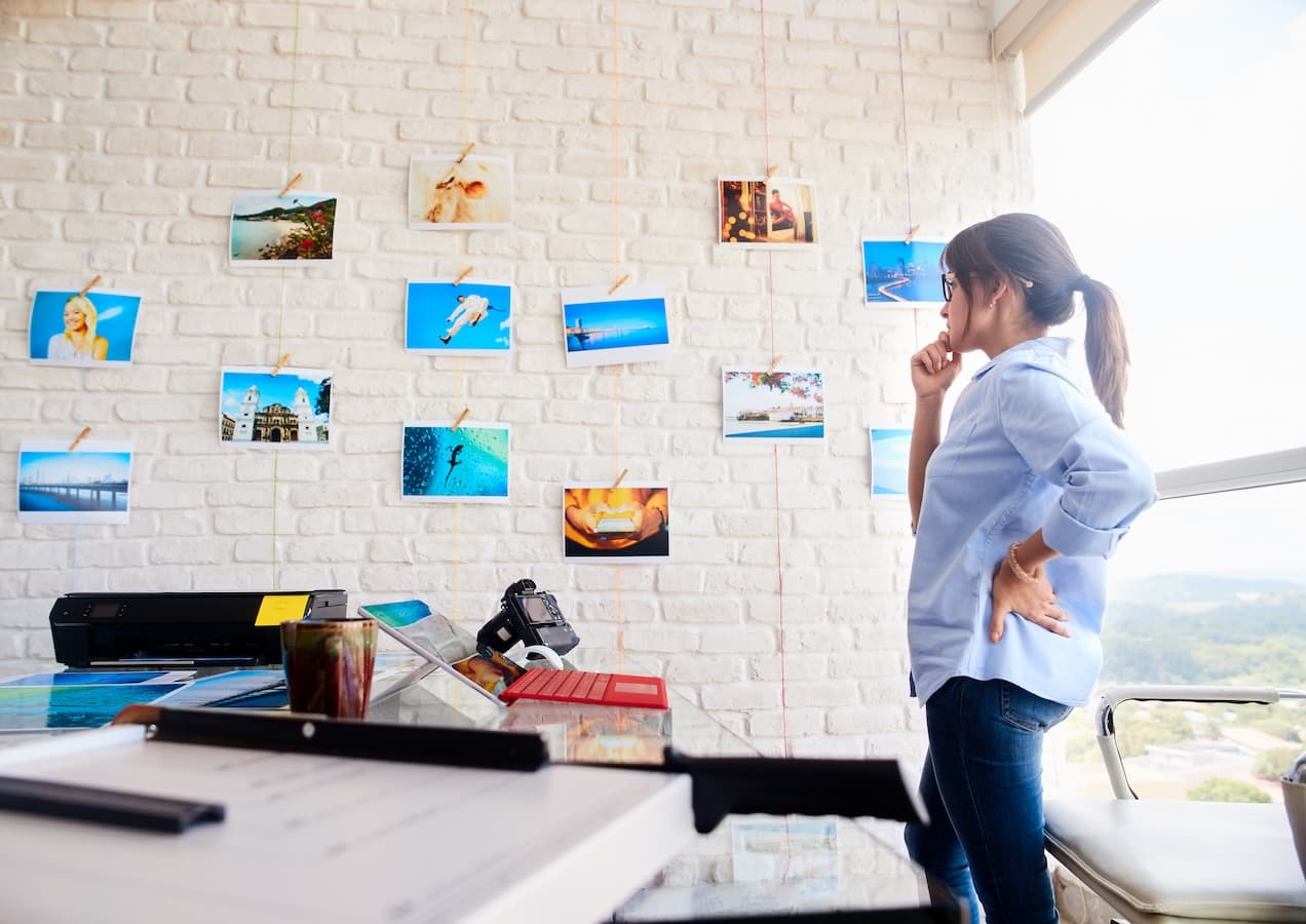 Travel agency owner planning trips beside a wall of destination photos
