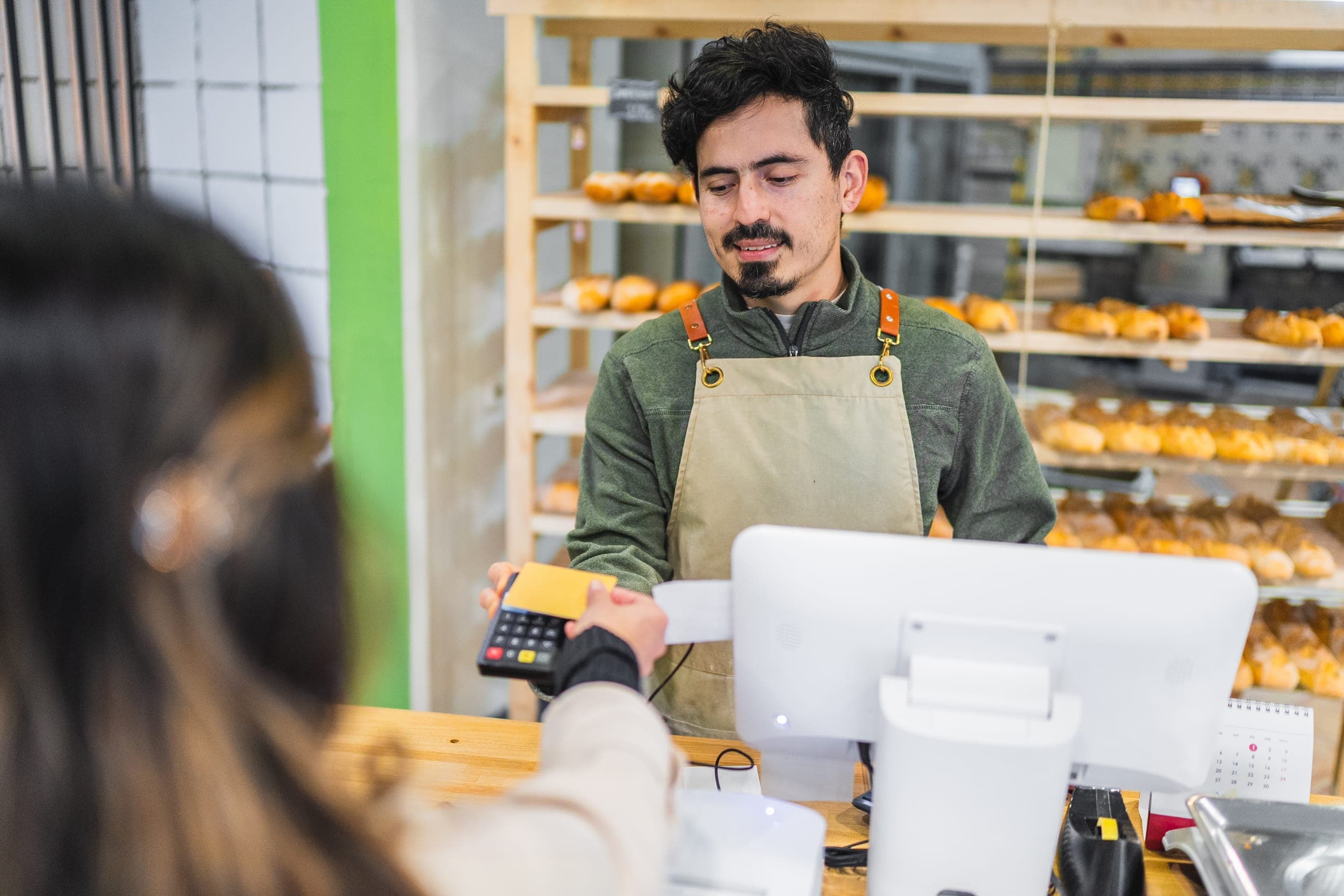 Bakery employee accepting a card payment through a payment gateway at checkout